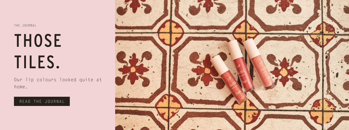 Those tiles — three Bloom Lip Glosses on patterned café floor tiles in Paris. Read the photoshoot story in the Journal.